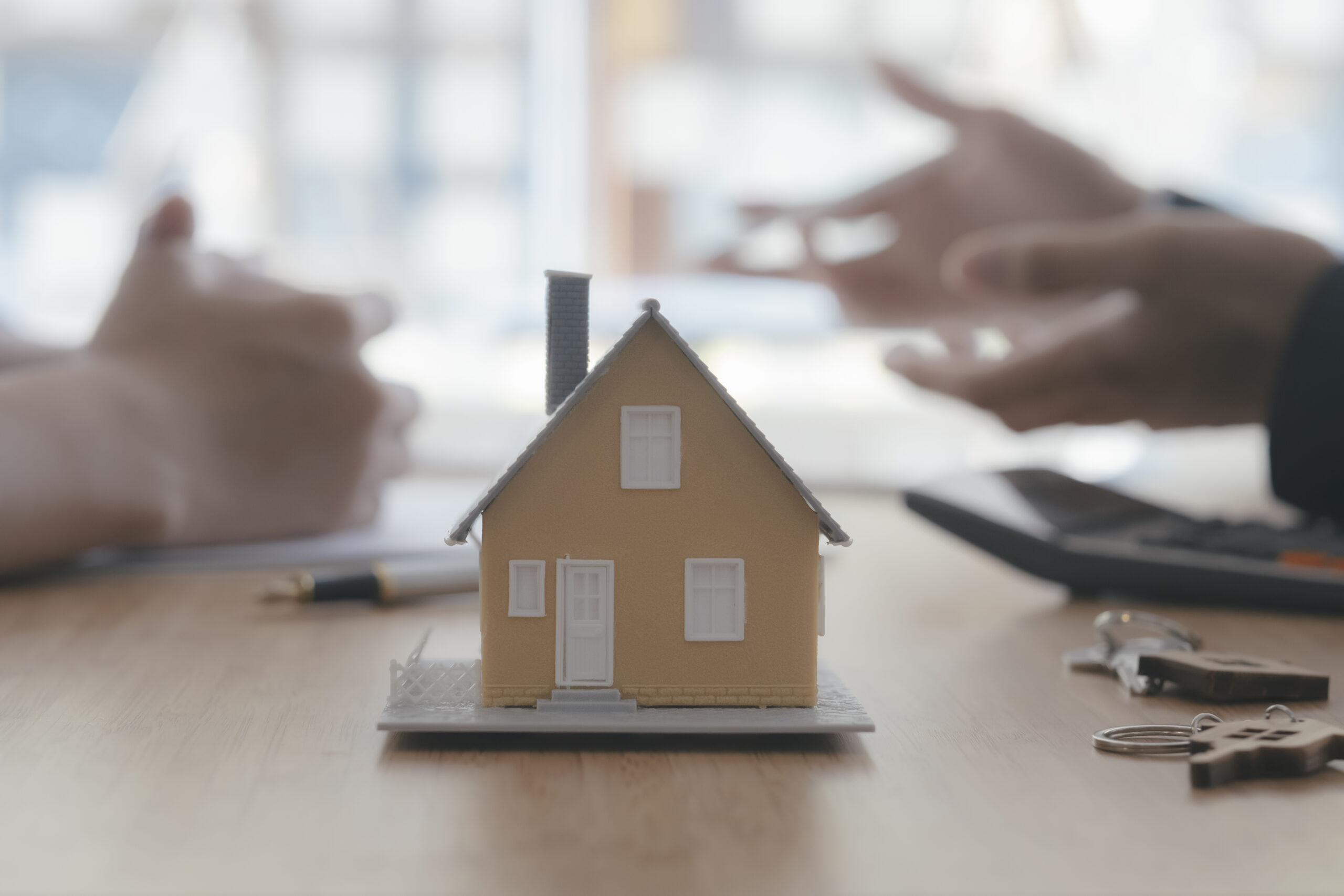 Close up house model on blur background of real estate agent and